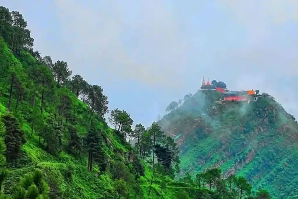 View of Monkey Point Kasauli from below with hilltop temple and lush greenery
